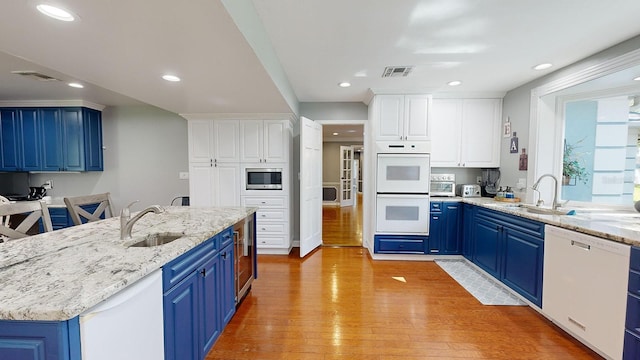 kitchen featuring white appliances, white cabinets, blue cabinets, and light wood-type flooring