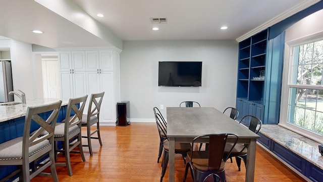 dining area featuring light wood-type flooring, sink, and a wealth of natural light