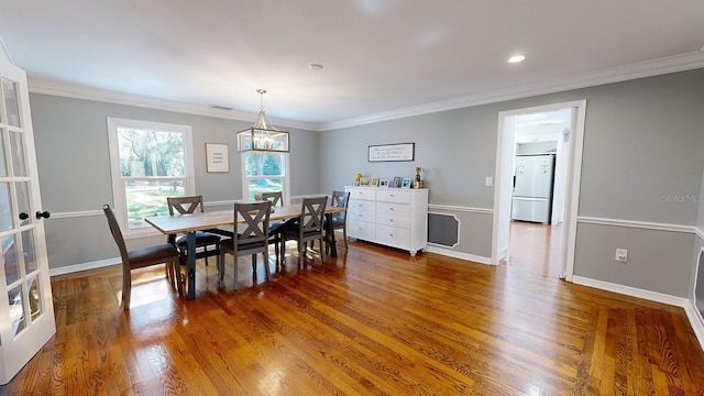 dining space with dark wood-type flooring and crown molding