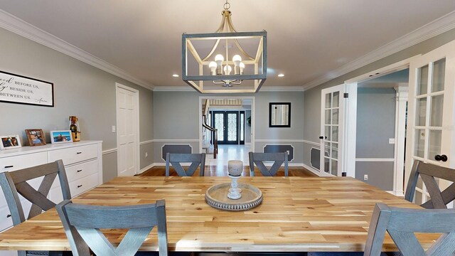 dining room featuring french doors, an inviting chandelier, light wood-type flooring, and crown molding