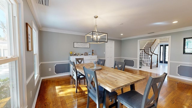 dining area with ornamental molding, hardwood / wood-style floors, and a notable chandelier