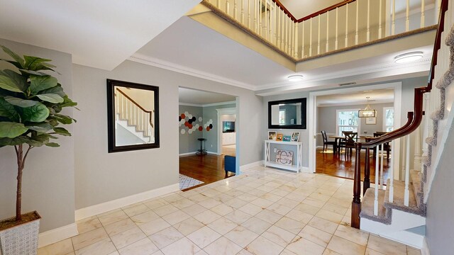 entryway with light hardwood / wood-style floors, crown molding, and a chandelier