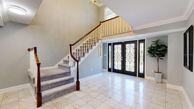 foyer featuring crown molding, a towering ceiling, and french doors