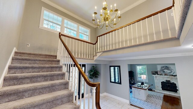 stairs with wood-type flooring, ornamental molding, and a chandelier