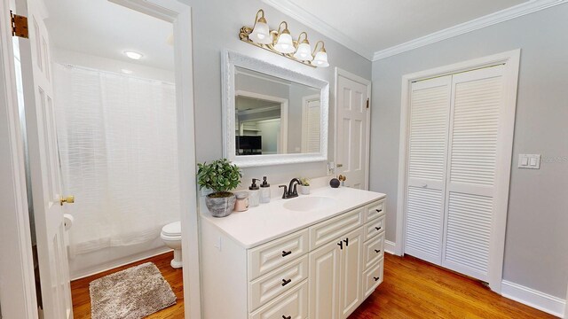 bathroom featuring curtained shower, vanity, crown molding, wood-type flooring, and toilet