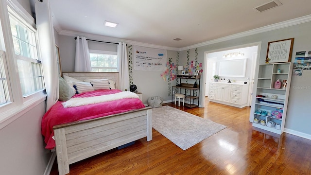 bedroom with wood-type flooring, ensuite bath, and crown molding