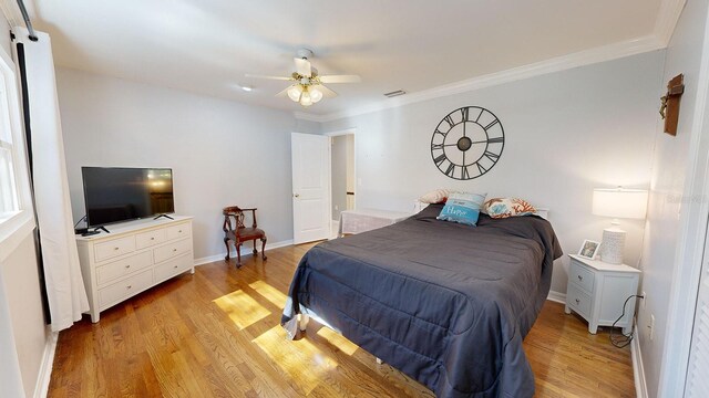 bedroom with crown molding, light hardwood / wood-style floors, and ceiling fan