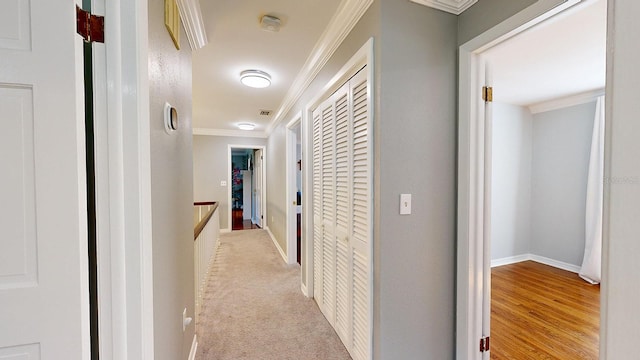 hallway with ornamental molding and light hardwood / wood-style flooring