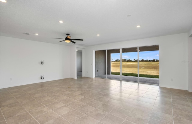 empty room with ceiling fan, a textured ceiling, and light tile patterned floors