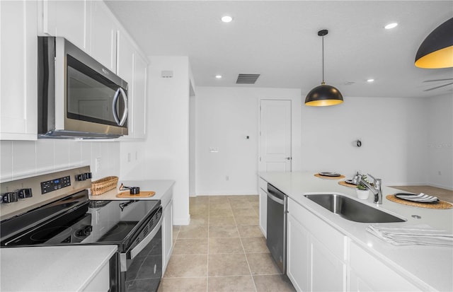 kitchen with light tile patterned flooring, appliances with stainless steel finishes, pendant lighting, sink, and white cabinets