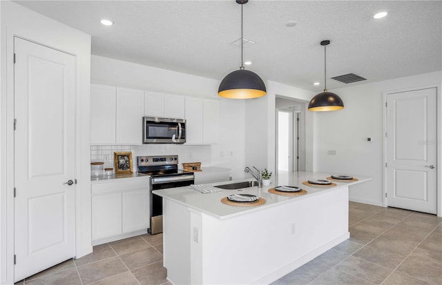 kitchen featuring pendant lighting, an island with sink, sink, white cabinets, and stainless steel appliances