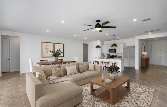 tiled living room with ceiling fan and a textured ceiling