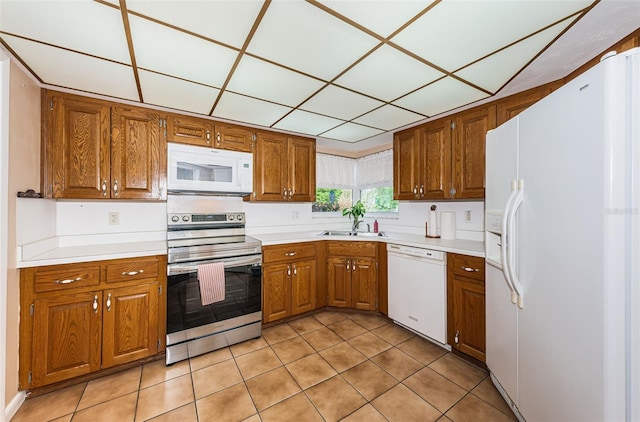 kitchen featuring brown cabinetry, white appliances, light countertops, and a sink