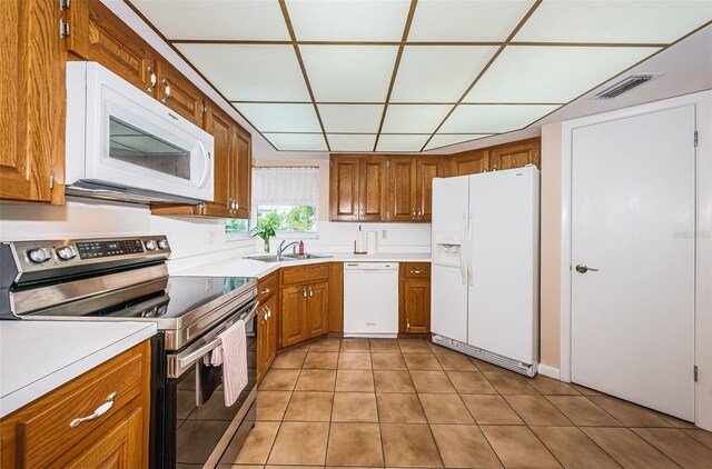 kitchen featuring brown cabinets, white appliances, visible vents, and a sink