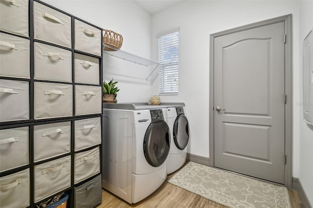 clothes washing area featuring washer and clothes dryer and light hardwood / wood-style flooring