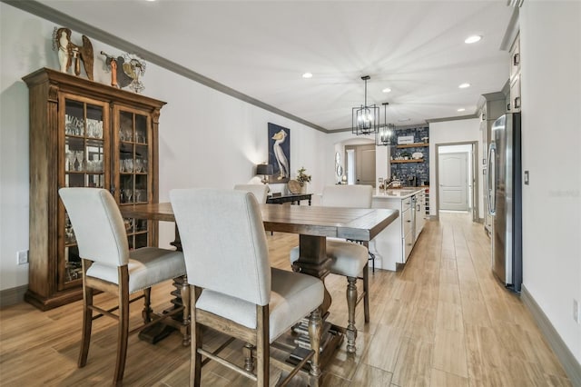 dining area featuring ornamental molding, a notable chandelier, and light wood-type flooring