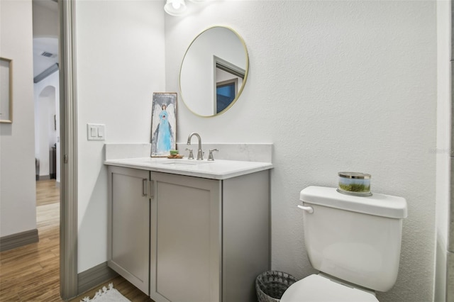 bathroom with toilet, hardwood / wood-style floors, and vanity