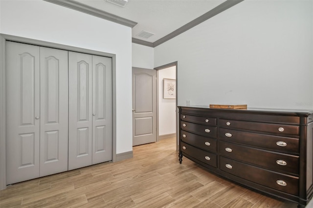 bedroom with a closet, light wood-type flooring, and crown molding