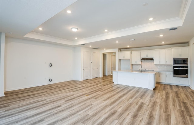 kitchen with wall oven, built in microwave, under cabinet range hood, decorative backsplash, and a raised ceiling