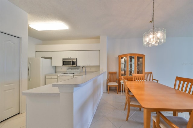 kitchen featuring a textured ceiling, white appliances, a notable chandelier, white cabinets, and pendant lighting