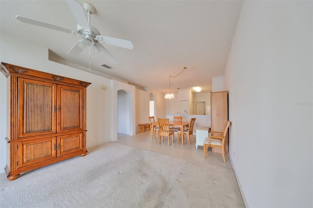 interior space featuring ceiling fan with notable chandelier, a textured ceiling, and light carpet