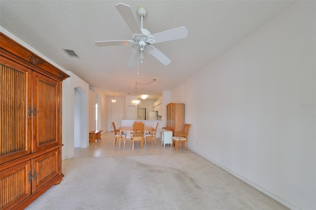 carpeted dining room with ceiling fan and a textured ceiling