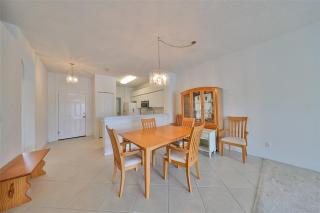 dining space with a chandelier, a textured ceiling, and light tile patterned flooring