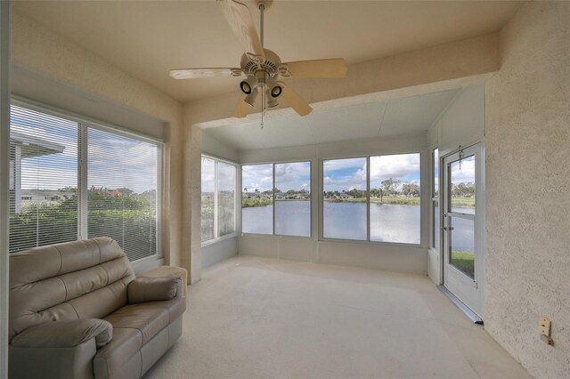 sunroom with ceiling fan and a water view