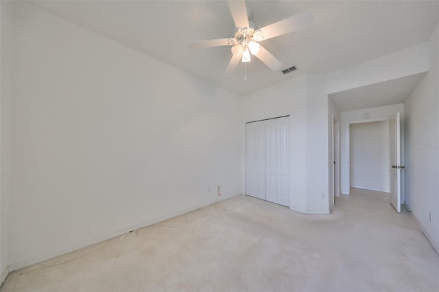 unfurnished bedroom featuring light carpet, ceiling fan, and a closet