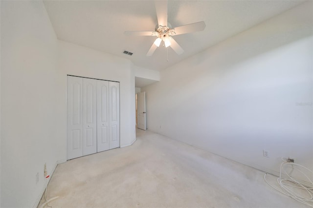 unfurnished bedroom featuring ceiling fan, light carpet, and a closet