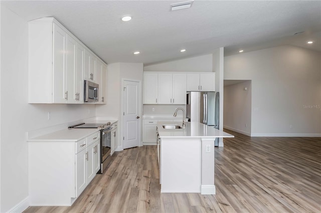 kitchen with white cabinets, an island with sink, lofted ceiling, sink, and stainless steel appliances