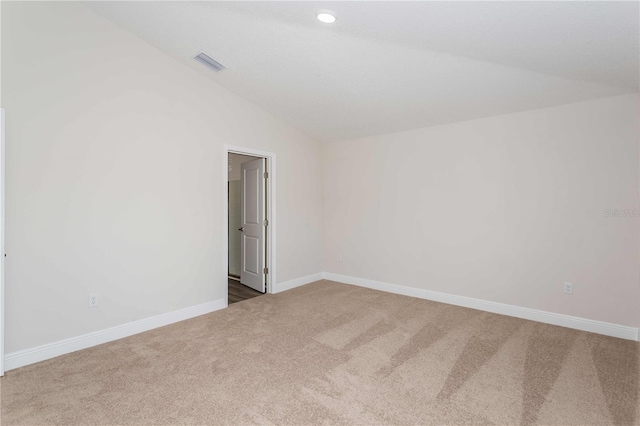 carpeted empty room featuring vaulted ceiling