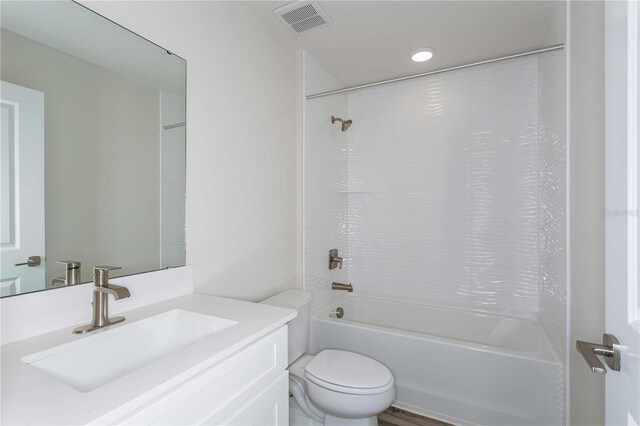 full bathroom featuring vanity, tiled shower / bath, and toilet