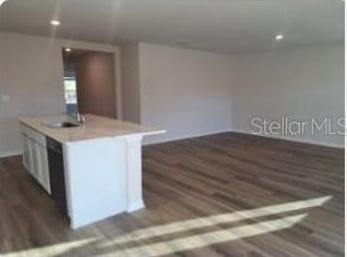 kitchen with a kitchen island with sink, sink, white cabinetry, and dark wood-type flooring