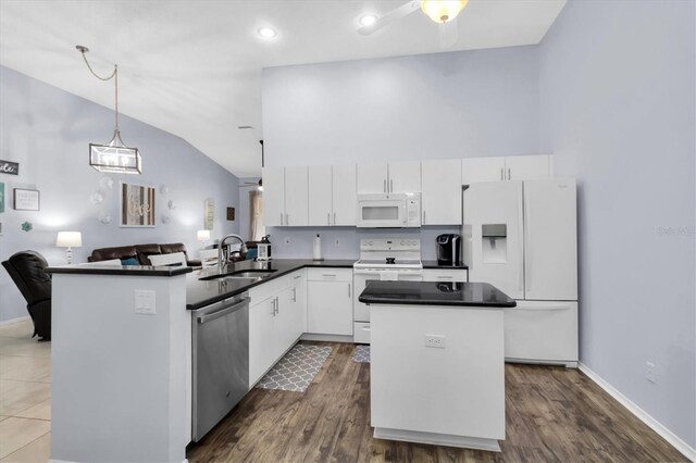 kitchen featuring white appliances, kitchen peninsula, white cabinetry, and sink