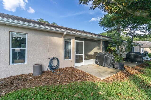 rear view of property featuring a sunroom and a patio area