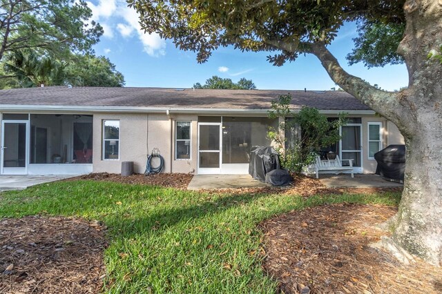 rear view of house featuring a lawn and a sunroom