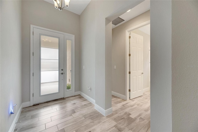 foyer with light hardwood / wood-style floors and a notable chandelier