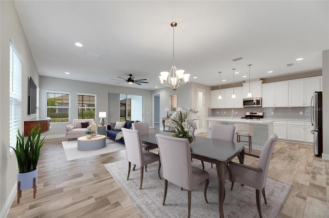 dining area featuring ceiling fan with notable chandelier and light wood-type flooring