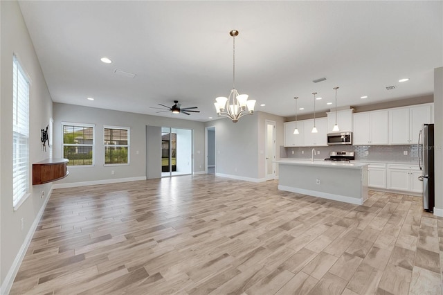 unfurnished living room featuring ceiling fan with notable chandelier and light hardwood / wood-style floors