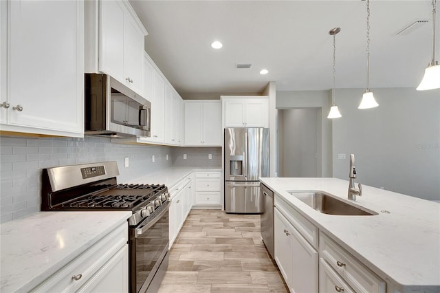 kitchen featuring pendant lighting, stainless steel appliances, sink, and white cabinets