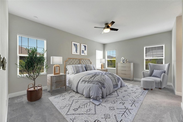 carpeted bedroom featuring multiple windows and ceiling fan