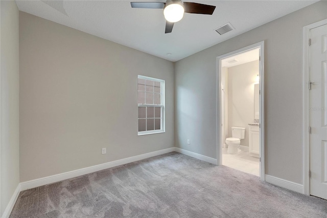 unfurnished bedroom featuring light colored carpet, ceiling fan, and ensuite bath