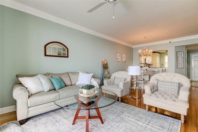 living room with hardwood / wood-style flooring, ceiling fan with notable chandelier, and crown molding