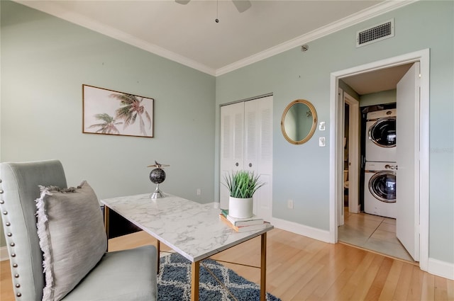 office area with wood-type flooring, stacked washer / dryer, ornamental molding, and ceiling fan