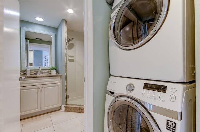 laundry room with light tile patterned floors, sink, and stacked washing maching and dryer