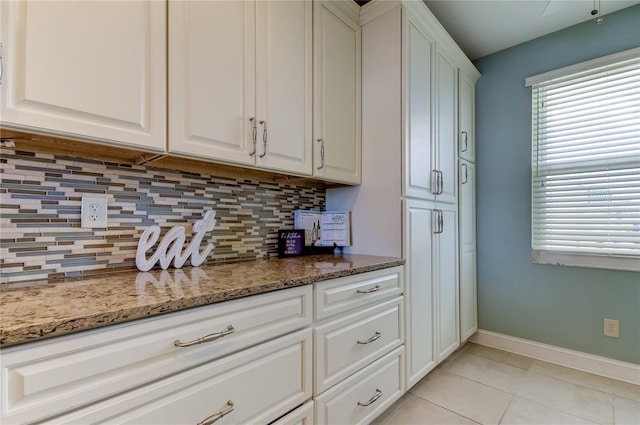 kitchen featuring dark stone counters, white cabinetry, decorative backsplash, and light tile patterned floors