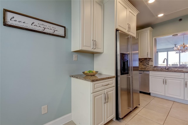 kitchen featuring tasteful backsplash, white cabinets, appliances with stainless steel finishes, light tile patterned floors, and dark stone countertops