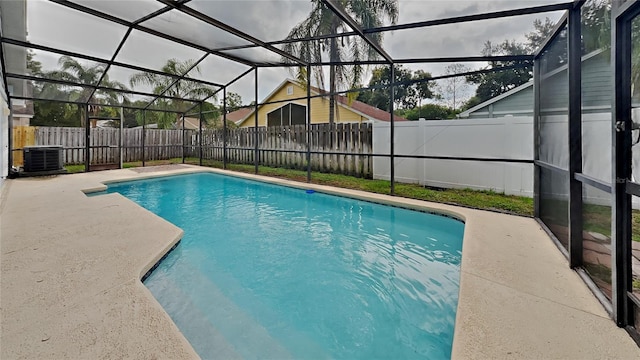 view of pool with glass enclosure, a patio, and central AC