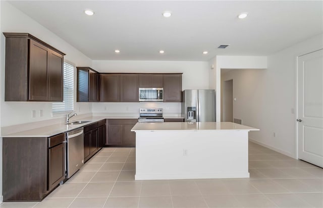 kitchen with dark brown cabinetry, stainless steel appliances, a center island, and sink